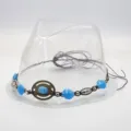 Close-up detail of vintage bohemian hat band accessory with blue beads and metal ring. - Dark Woven Cord Band With Blue Artificial Turquoise And Distressed Copper Ring