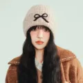 Detailed shot of a cute winter knitted beanie for women featuring a sweet black bow design. - One Size / Khaki