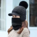 Primer plano detallado del cálido gorro de invierno de punto negro con pompón suave y orejeras. - Solo Gorro / Negro