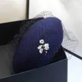 Nahaufnahme eines marineblauen Woll-Baskenmützen mit elegantem Netz und Blumen-Brosche-Detail - Verstellbar / Marineblau