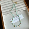 Detailed view of turquoise green beaded necklace featuring golden clover flower charms - Green Stone Necklace