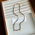 Close-up of tiger eye stone necklace with gold clover charms on jewelry tray - Tiger Eye Necklace