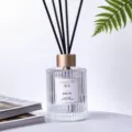 Detalle de difusor de aromas amaderados de cedro, botella de vidrio estriado con varillas negras. - Dominio de cedro