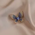 Exquisite blue crystal butterfly brooch detail, elegant gold metal rhinestone lapel pin. - Blue