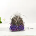Detail view of a white mesh sachet bag filled with aromatic dried lavender and plant particles. - Lavender (Dried Lavender)