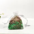 Detailed close-up of a white organza sachet bag filled with aromatic dried herbal plant particles. - Green Tea (Lemongrass)