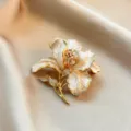 Exquisite enamel flower brooch featuring sparkling rhinestones and pearls. Vintage golden pin. - White