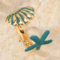 Vista dettagliata di un anello aperto dorato con conchiglia e stella marina in smalto blu. - Imitazione oro blu lago (M1706)