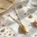 Seashell pendant necklace detail shot featuring gold chain and beach-themed styling props. - 3D Conch Pendant (Style 8) / Gold
