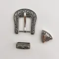 Close-up detail shot of vintage metal belt buckle three-piece set with intricate floral carving. - Silver Buckle