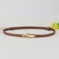 Slim genuine leather belt for women featuring a vintage gold heart buckle. Detail view. - Caramel color