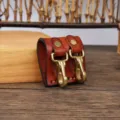 Close up detail of brown leather belt key holder with dual solid brass hooks and metal rivets. - Brown