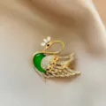 Elegant swan brooch with green stone and sparkling crystals, perfect fashion accessory. - Gold
