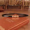 Close-up van de smalle zwarte lederen riem met gouden draaisluiting metalen gesp voor dames. - Zwart