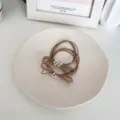 Set of pearl bow elastic hair ties in minimalist beige on ceramic display dish - Camel