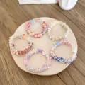 Lot d'élastiques à cheveux texturés colorés pour femmes sur une assiette en céramique - 5 Pièces / Style Perles Colorées