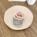 Set of five pastel-colored braided elastic hair ties presented on a beige ceramic plate - 5 Pieces / 4-Strand Thick and Thin Braid