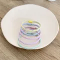Pastel braided elastic hair ties in a stack on a white ceramic plate - Thin Twisted Style