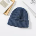 Detailed view of stylish blue knitted beanie hat with embroidered front, warm winter cold hat. - Navy Blue