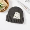 Dunkelgraue Strickmütze mit niedlichem weißen Patch und lächelndem Gesicht, warmer Winter. - Einheitsgröße / Grau