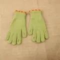 Detailed view of winter knitted gloves, cute pom-pom cuffs and fingerless green design. - One Size / Green