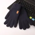 Close-up of navy blue knitted touch screen gloves placed on laptop keyboard for detail view. - One Size / Navy Blue Patched