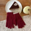 Close-up detail of red knitted winter gloves with white ribbed cuffs on a cozy wooden table. - One Size / Burgundy