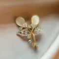 Detailed close-up of gold leaf rhinestone brooch, sparkling crystals and chic design. - Gold