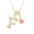 Macro view of gold pendant with zircon letter F and pink teardrop planet charm - Letter F