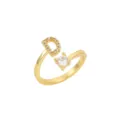 Détail d'une bague dorée ajustable avec la lettre D pavée et une pierre claire - Lettre D