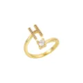 Détail d'une bague ouverte dorée avec une lettre H scintillante et un cristal rond - Lettre H