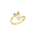 Détail d'une bague ouverte dorée ornée d'un 'M' scintillant et d'un cristal - M