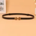 Detailed shot of a women's black thin leather belt with antique gold decorative knot buckle. - Black