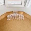 Große transparente Haarklammer für Damen auf einem minimalistischen Korktablett serviert - Großer Drachenknochen