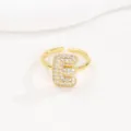 Detail van een vergulde bubble letter E-ring bezet met fonkelende zirkonia-steentjes - Letter E Stijl