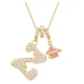 Macro detail of gold necklace featuring iced-out letter S and pink planet charm with star - Letter Z