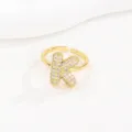 Detailweergave van een goudkleurige open ring met een sprankelende letter K bezet met zirkoon. - Letter K Stijl