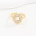 Close-up van een goud vergulde verstelbare ring met een cirkel van zirkonia steentjes - Letter O Stijl
