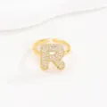 Gedetailleerde weergave van een goudkleurige bubble letter R-ring met pavé. - Letter R Stijl