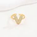Detailweergave van een gouden verstelbare ring met een letter V bezet met zirkonia's - Stijl Letter V