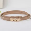 Primo piano della sottile cintura da donna in pelle beige con elegante chiusura a lucchetto. - Kaki