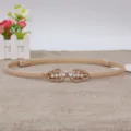 Close-up detail of the elegant thin leather waist belt with gold leaf pearl buckle. - Apricot