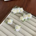 Elegante camelia bloem haarclips met groene bladeren op een houten sieradendisplay - Gemengd Crèmewit Set