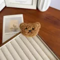 Vue détaillée d'une jolie broche d'ours en peluche marron sur un plateau en bois - Café Foncé
