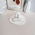 Une pince à cheveux douillette en peluche blanche avec un nœud argenté sur un plateau - Blanc Cassé