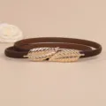 Detailed view of the brown leather thin belt with elegant gold leaf buckle closeup. - Coffee