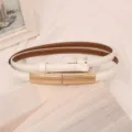 Primo piano di un'elegante cintura sottile in pelle bianca con fibbia in metallo dorato. - Bianco