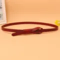 Primo piano di una sottile cintura in pelle bordeaux da donna con design a nodo - Rosso