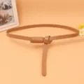 Detail of a thin brown women's leather belt tied in an elegant decorative knot style. - Apricot