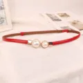 Vista dettagliata di un'elegante cintura rossa sottile con decorazioni di perle per abiti da donna. - Rosso